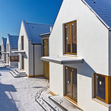 A photograph of sleek, modern houses with snow on the ground and the roofs on a crisp winter day.